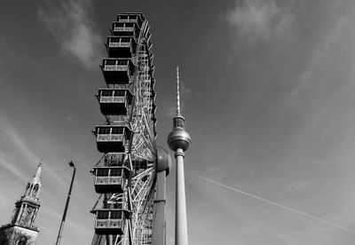 Low angle view of ferris wheel by fernsehturm against sky