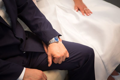 Midsection of newlywed couple holding hands sitting in wedding ceremony