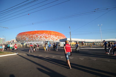 People walking on road against blue sky