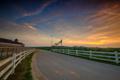 Road by bridge against sky during sunset