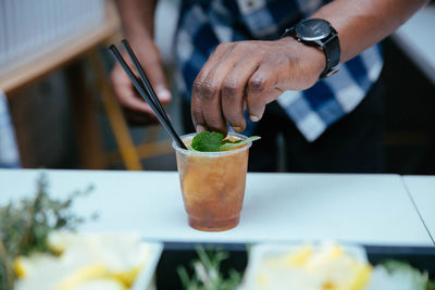 Close-up of hand holding drink on table