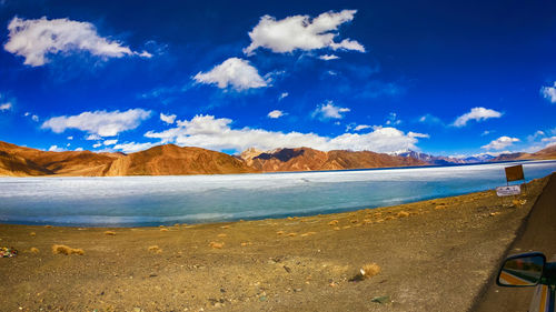 Scenic view of sea and mountains against blue sky