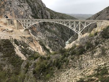 Arch bridge over mountains against sky