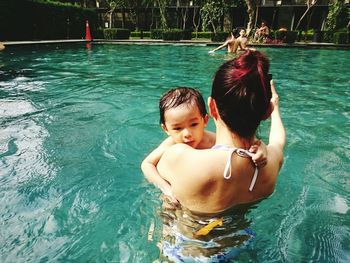 Rear view of woman with son in swimming pool