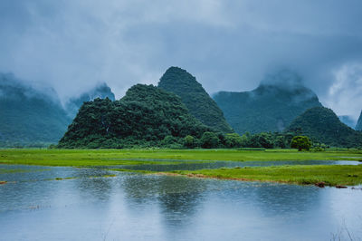 Scenic view of lake by mountains against sky