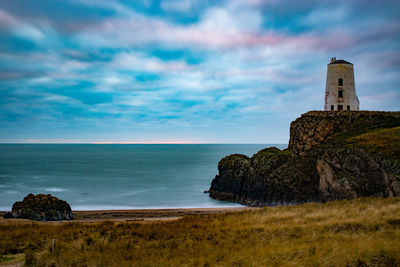 Lighthouse by sea against sky