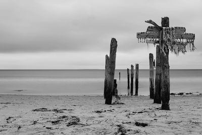 Cross sculpture on beach against sky