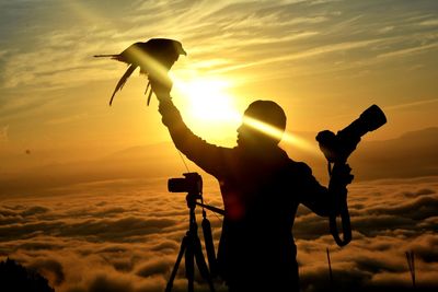 Silhouette man photographing at sunset