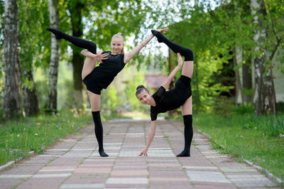 Portrait of girls practicing rhythmic gymnastics on footpath in park