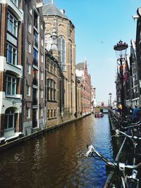 Canal amidst buildings in city against sky