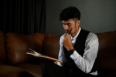 Man with hand on chin reading book