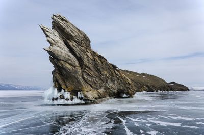 Rock formation on beach against sky