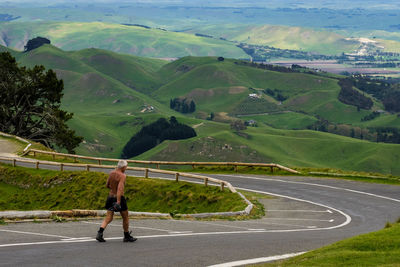 Rear view of a man walking on road