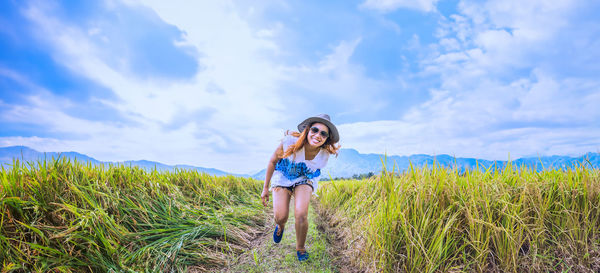 Rear view of woman standing on field against sky