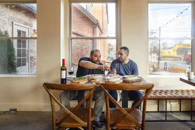 Two men share a meal an bottle of wine together in an empty restaurant