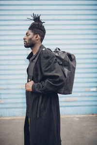 Side view of young man standing against wall