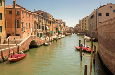 Boats moored in canal amidst buildings in city