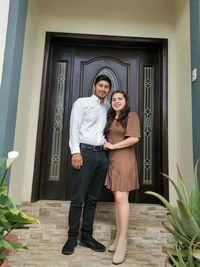 Portrait of young woman standing against door