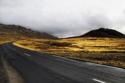 Empty road by mountain against sky