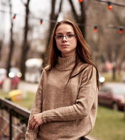 Portrait of young woman wearing eyeglasses and sweater in city