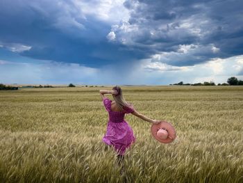 Rear view of woman standing on field against sky