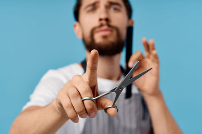 Portrait of young man holding hands against blue background