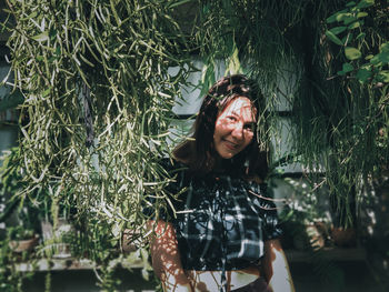 Portrait of smiling woman standing against plants