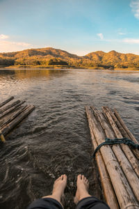 Low section of people on lake against sky