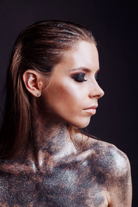 Close-up of young woman against black background