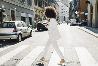 Businesswoman using phone walking on city street