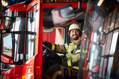 Firefighter looking away while sitting in fire truck at fire station