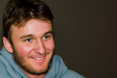 Portrait of smiling young man against black background