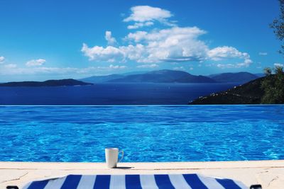 Cup at poolside against sky