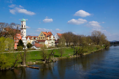 Buildings by lake against sky