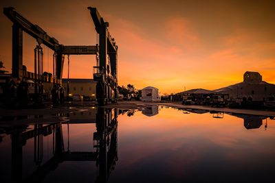 Cranes at lake against sky during sunset