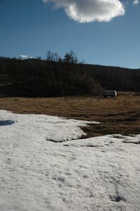 Snow covered field against cloudy sky