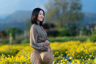 Portrait of a smiling young woman standing on field