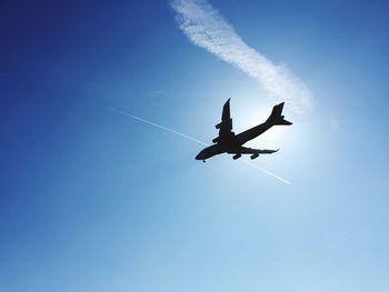 Low angle view of airplane flying against blue sky