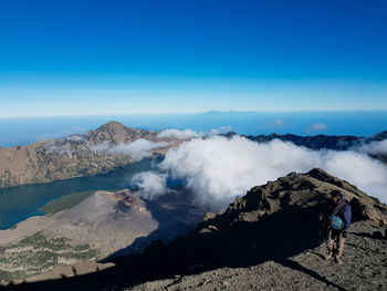 Man standing on volcanic mountain against blue sky