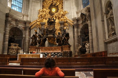 Rear view of woman sitting in st peters basilica