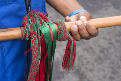 Midsection of person holding bamboo with ribbons