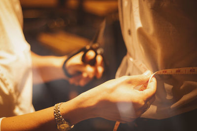 Close-up of woman measuring customer waist for stitching clothes