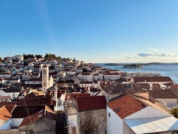 High angle view of townscape by sea against sky
