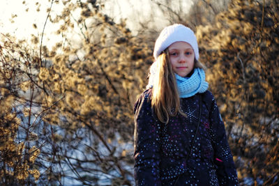 Portrait of girl against dried plants during winter