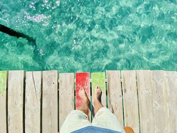 Low section of man relaxing on pier over sea