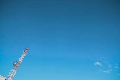 Low angle view of cranes against clear blue sky