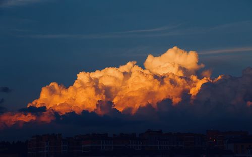 Smoke emitting from buildings against sky at sunset
