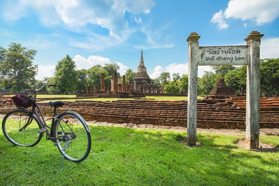 Bicycle parked on field against building