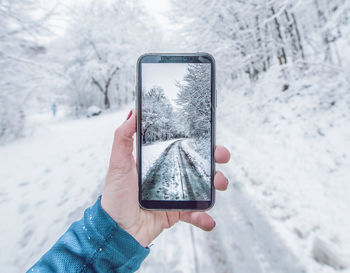 Close-up of person holding smart phone in snow