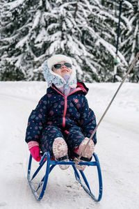 Rear view of woman sitting on snow